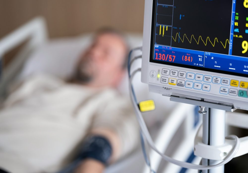 a man laying in a hospital bed next to a monitor